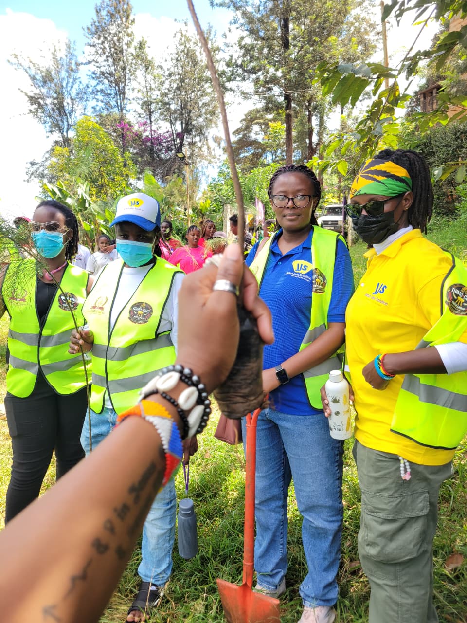JJS team and community members holding saplings together